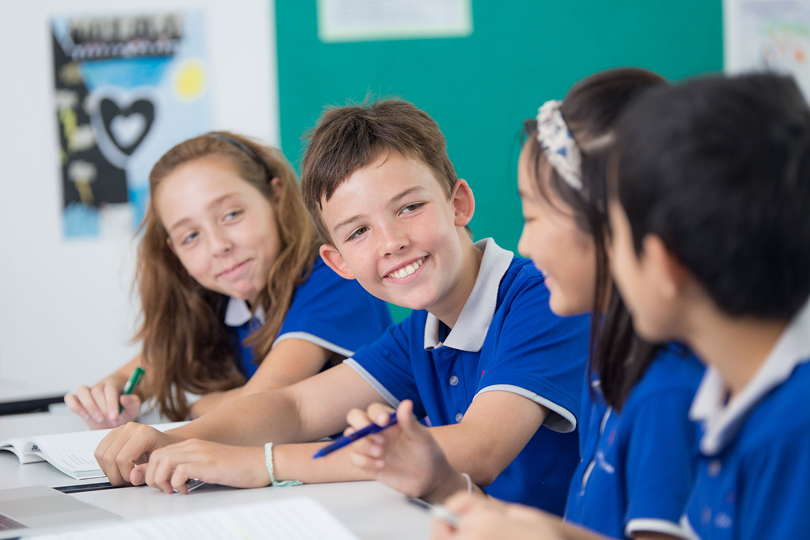 Four OFS Middle School students smiling while conversing in the classroom