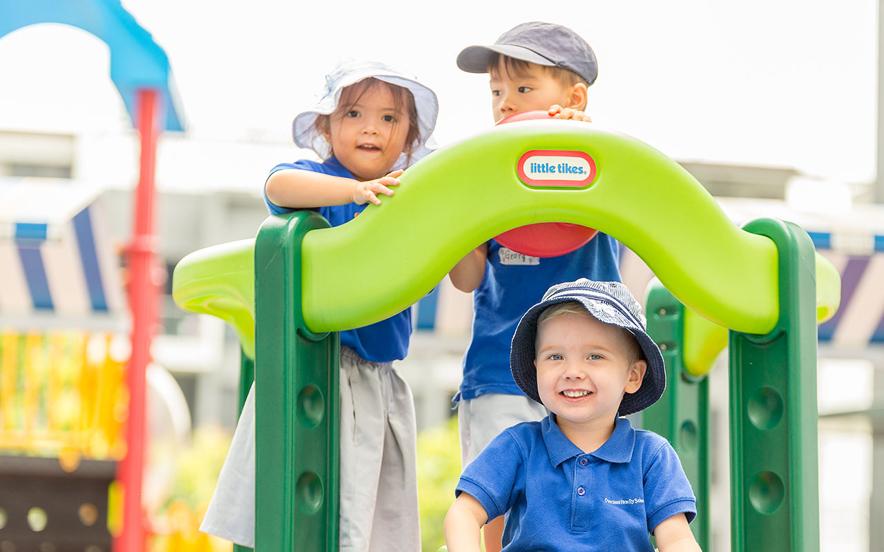 Three OFS Kindergarten students playing in the playground