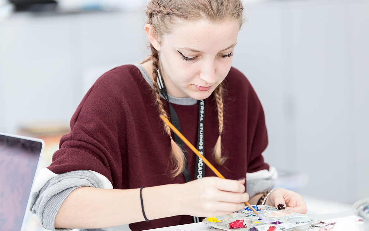 A female OFS Senior High School student mixing paint during art lesson in the High School Art room