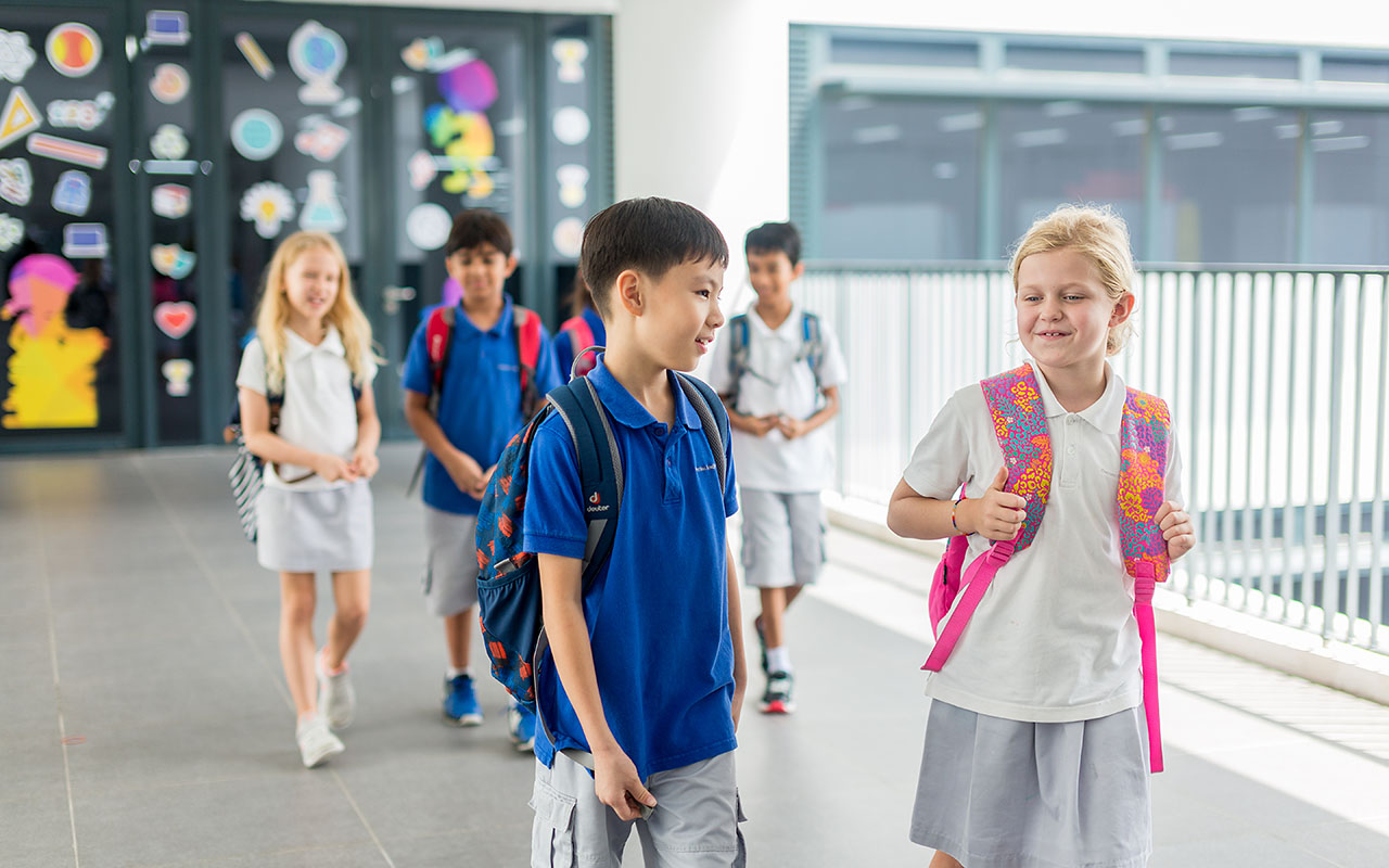 A group of OFS Elementary School students walking and conversing outside the OFS Junior block