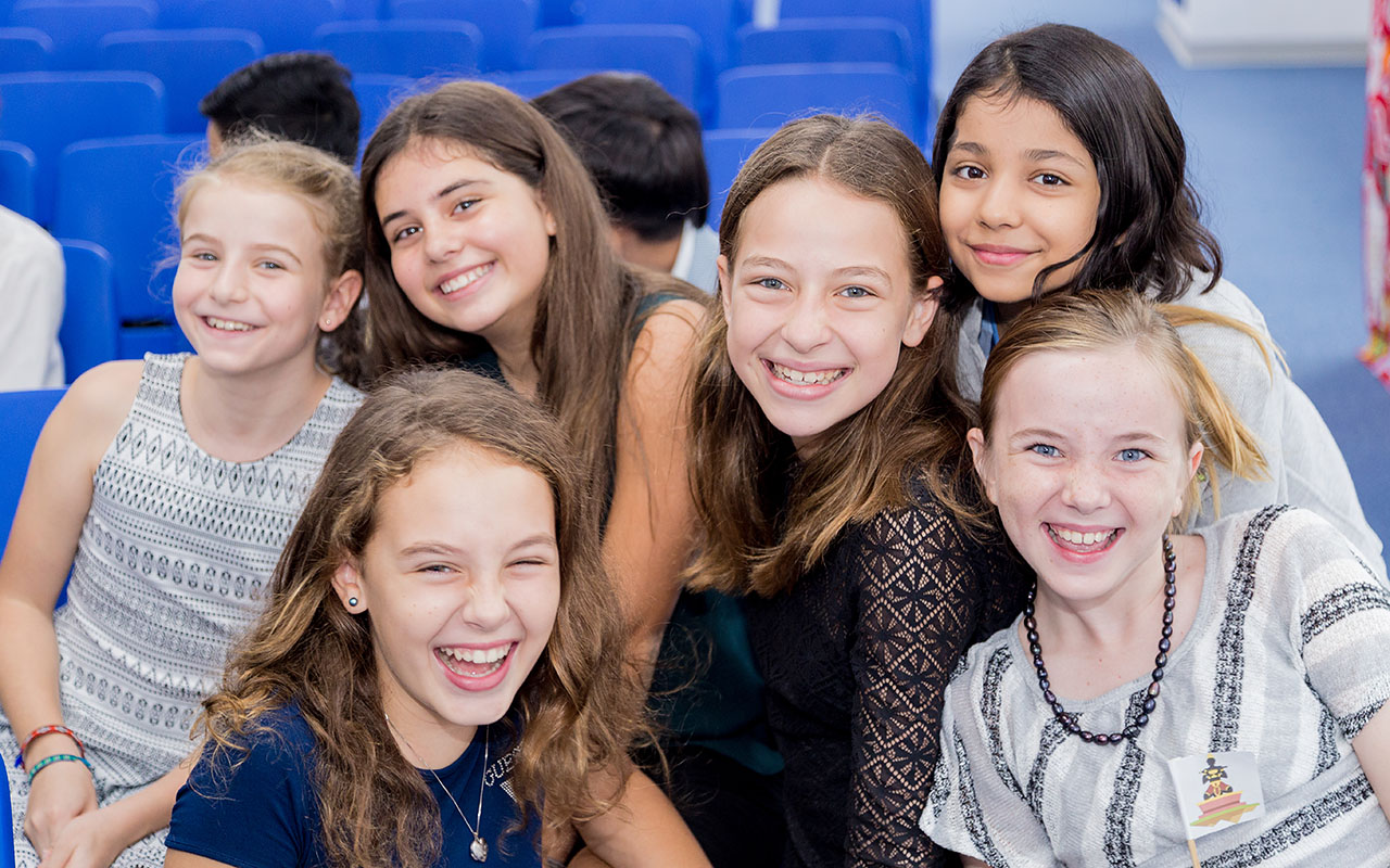 A group of female OFS Middle School students smiling in the activity room during Middle School Model United Nations (MY-MUNOFS)