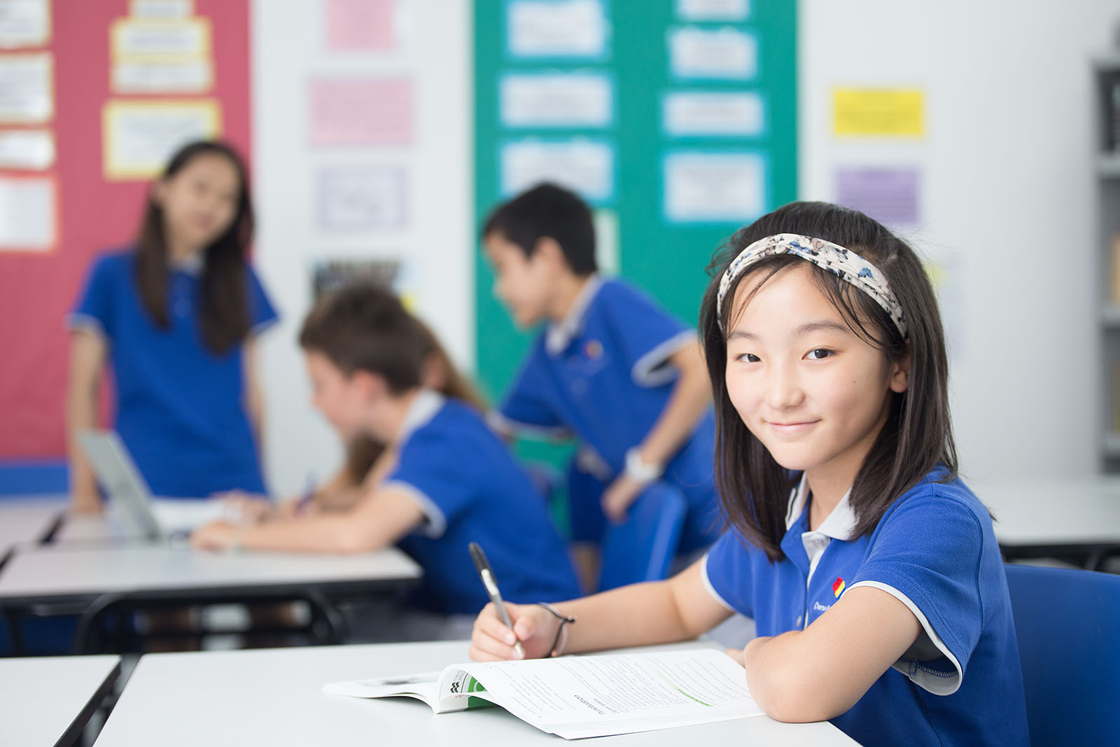 A female OFS Middle School student smiling to the camera while studying in the classroom