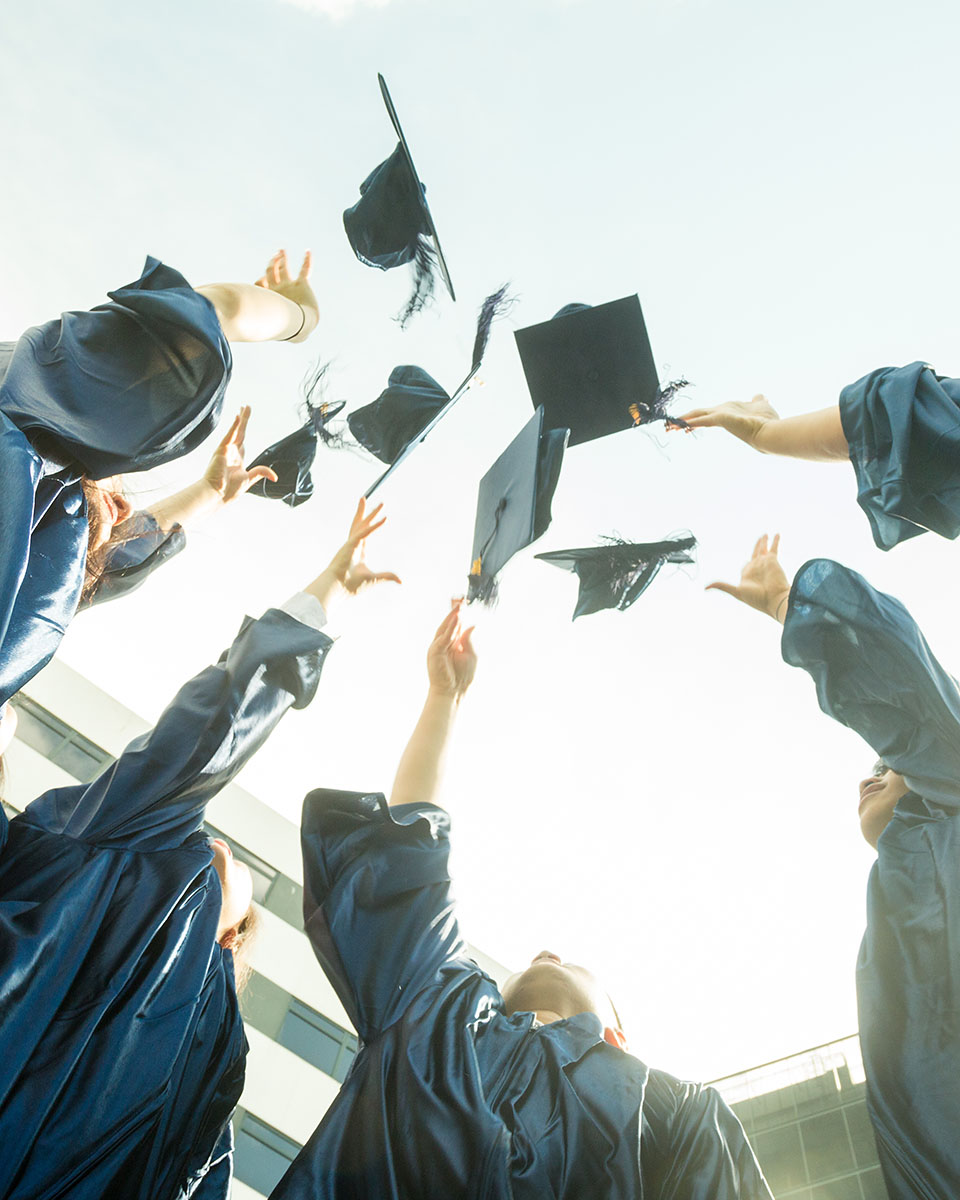 OFS High School graduates throwing their graduation hat in the air
