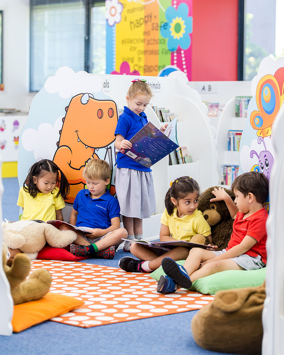 Five OFS Kindergarten students reading books in the Kindergarten Library