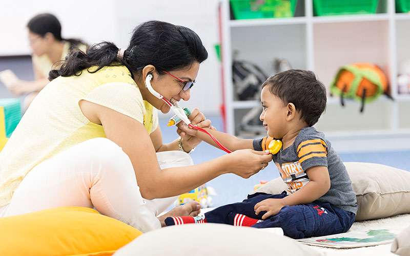 A mother and her toddler son playing doctor during OFS Playgroup session