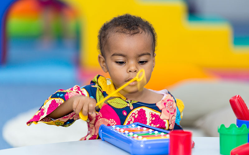 A female toddler playing with toy musical instrument during OFS Playgroup session