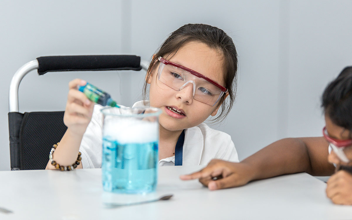 A female OFS Middle School student pouring a chemical inside a flask during science lab lesson