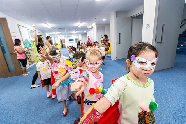 OFS Kindergarten students in superhero costumes parading around the school halls
