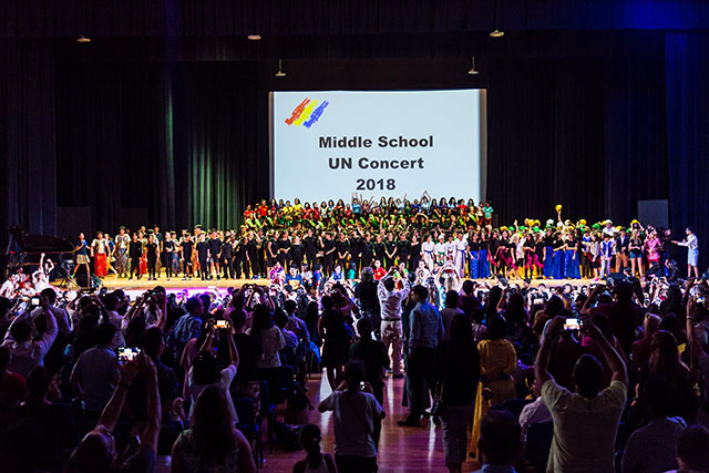 OFS Middle School student performers on the auditorium stage receiving standing ovation from parents
