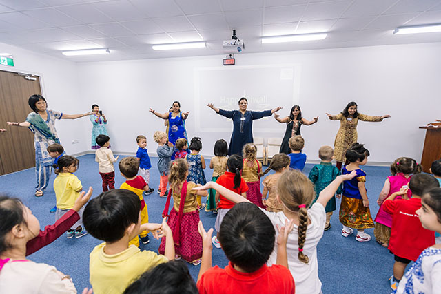 OFS Kindergarten students and teachers in traditional Indian outfits singing and dancing in activity room