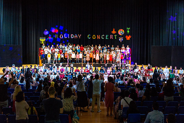 OFS Elementary School students performing songs on the stage while parents watch