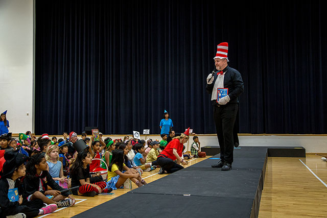 OFS Elementary School Principal in book character costume giving speech in auditorium while students listen