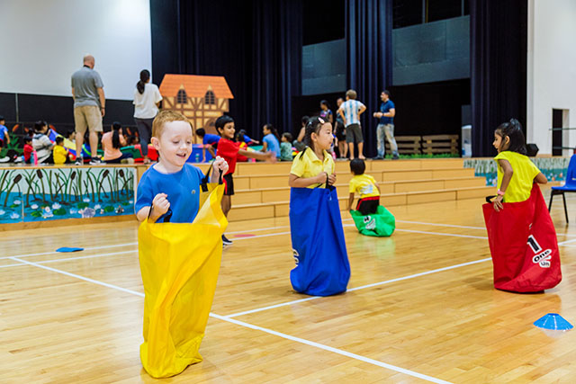 OFS Kindergarten students competing in sack run in auditorium