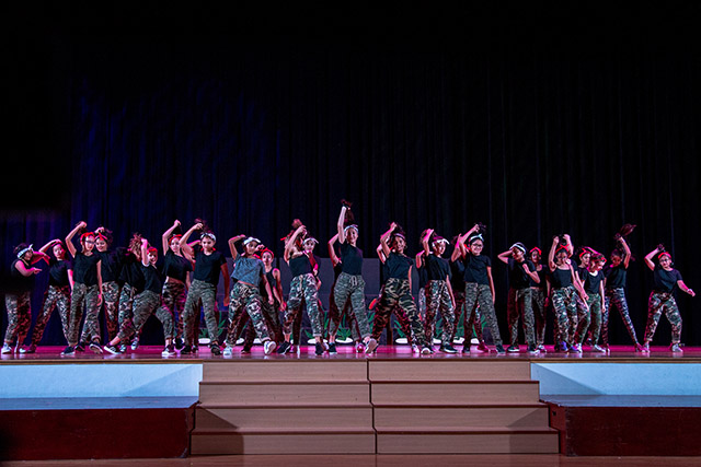 OFS Middle School students performing dance routine on the auditorium stage