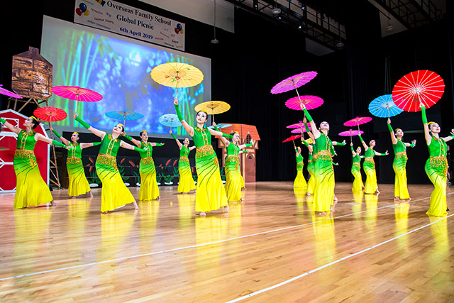 OFS Chinese parents performing traditional dance on the auditorium stage