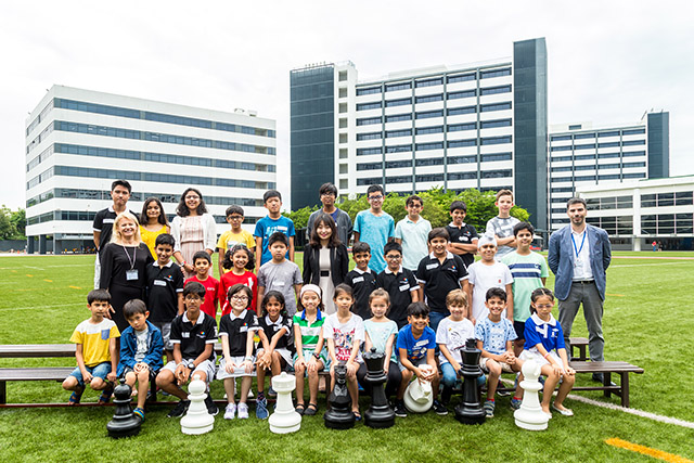 OFS students and Chess teachers posing for photo with Grand Master Ju Wenjun on OFS football field
