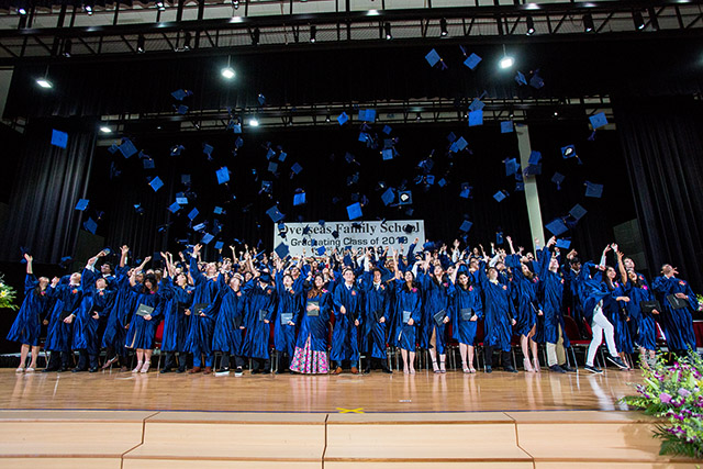 OFS High School graduates throwing their graduation caps in the air at the end of graduation ceremony