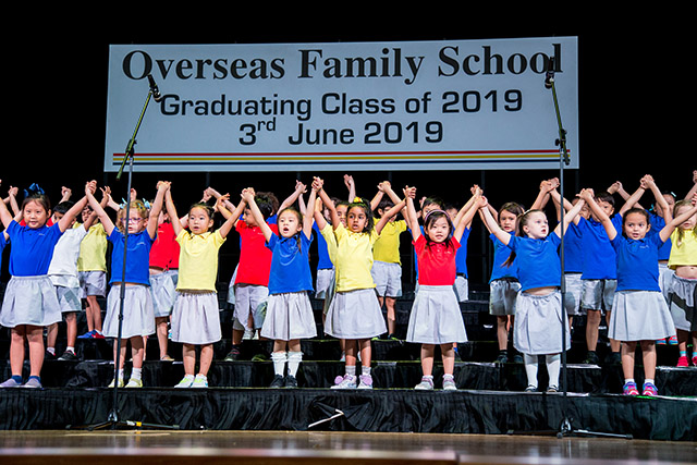 OFS Kindergarten K2 graduates singing on the auditorium stage