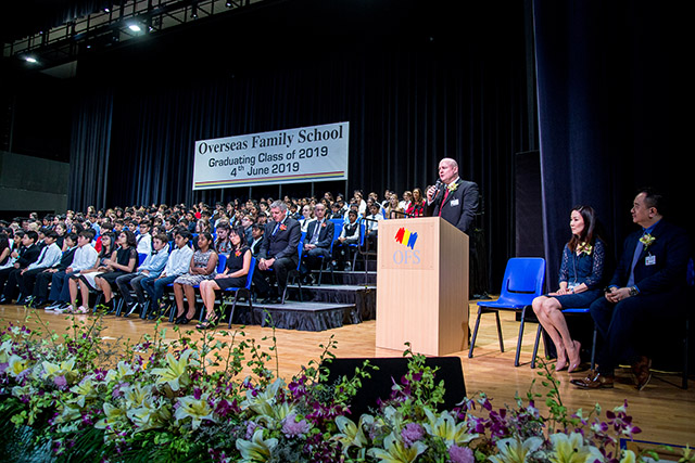 OFS Elementary School graduates sitting on the stage while Elementary School Principal is giving speech