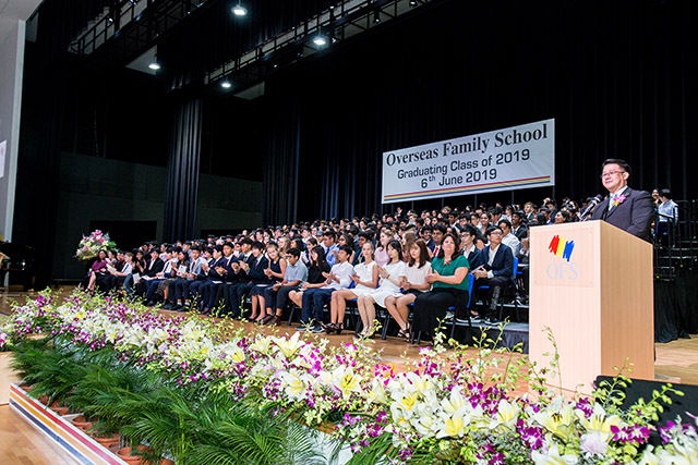 OFS Middle School graduates sitting on the stage while Middle School Principal is giving speech