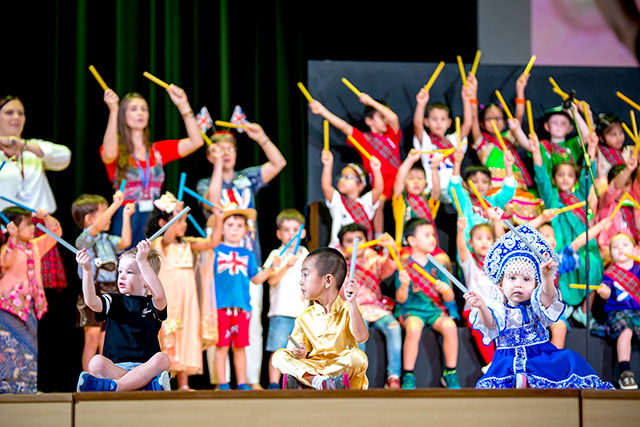 OFS Kindergarten students performing songs and dance on the auditorium stage