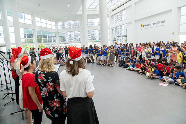 OFS Middle School teachers and students christmas carolling in the Atrium while parents and students watch